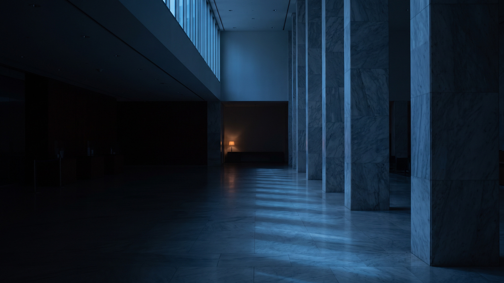A vast marble hall at blue hour with cool light raking across the floor